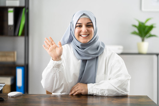 Muslim Woman Portrait Waving Hello In Video Conference - 写真・画像