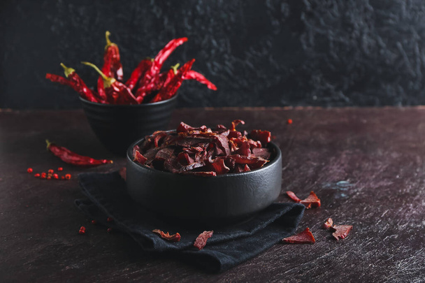 Bowl with spicy beef jerky on dark background - Zdjęcie, obraz