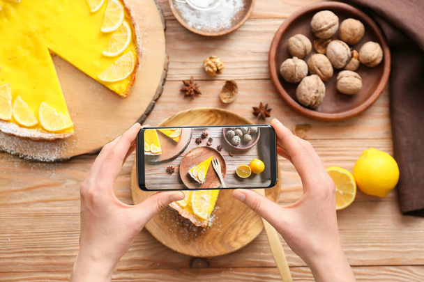 Woman with mobile phone taking photo of tasty lemon tart on table - Foto, Imagem