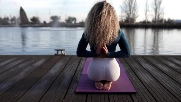 pretty blonde woman doing yoga at sunset in a lakepretty woman yoga teacher on a lake at sunrise - Filmmaterial, Video