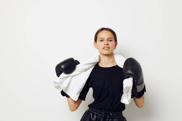 athletic woman in boxing gloves in black pants and a T-shirt isolated background - Photo, image