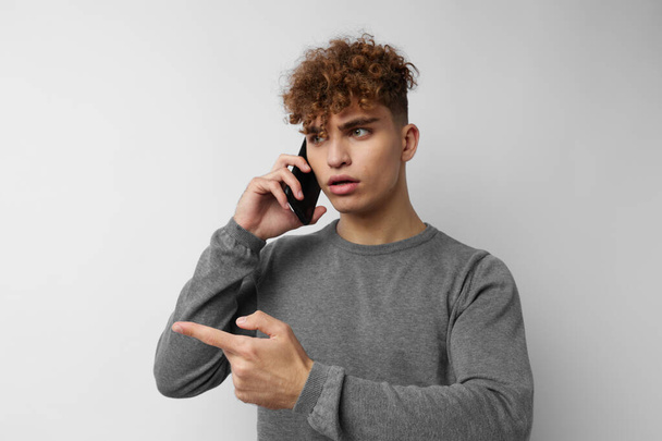 όμορφος νεαρός άνδρας με ένα τηλέφωνο στο χέρι επικοινωνία απομονωμένο υπόβαθρο - Φωτογραφία, εικόνα