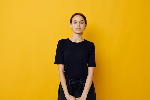 beautiful girl in a black T-shirt and pants smile yellow background - Fotografie, Obrázek
