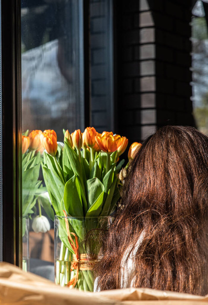 Unrecognizable young brown-haired woman and vase with red tulips. Festive spring concept. Faceless photography trend. - Valokuva, kuva