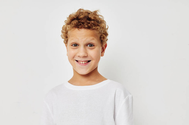curly boy in a white t-shirt posing fun childhood unaltered - Foto, afbeelding