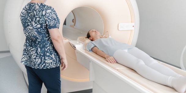 Doctor or nurse and patient with tomography CT or MRI Scan in hospital. Interior of radiography department. Technologically advanced equipment in white room. Magnetic resonance diagnostics machine - Photo, image