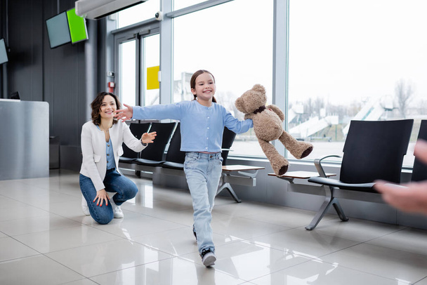 happy kid with teddy bear welcoming blurred father in airport  - Fotó, kép