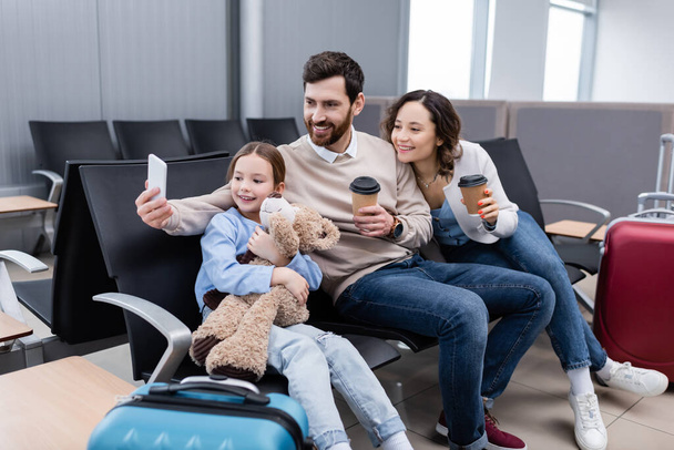 щасливий чоловік бере селфі з веселою сім'єю в залі для аеропортів
  - Фото, зображення