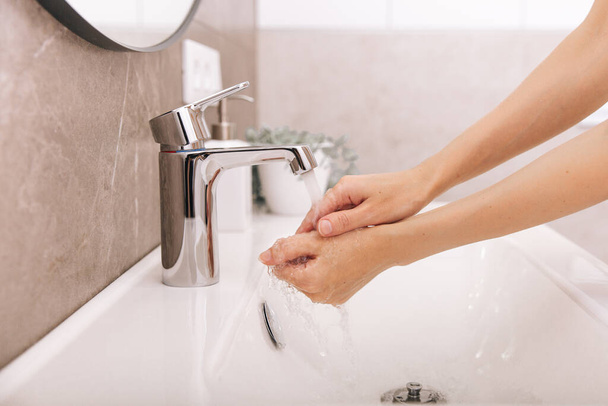 Washing hands under the flowing water tap. Washing hands rubbing with soap for corona virus prevention, hygiene to stop spreading corona virus in or public wash room. Hygiene concept hand detail - Foto, Imagen