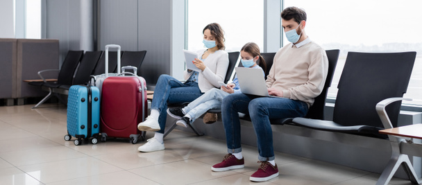 family in medical masks using gadgets in airport, banner - Foto, Imagen