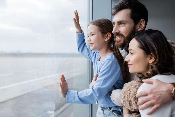 positive family looking at window in airport  - Foto, Bild