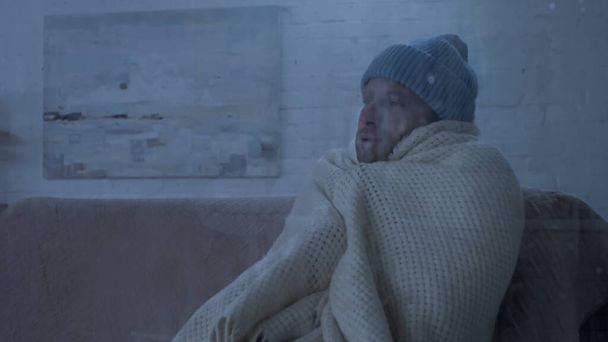 Sıcak bereli ve battaniyeli hasta adam evdeki kanepede oturuyor. - Fotoğraf, Görsel