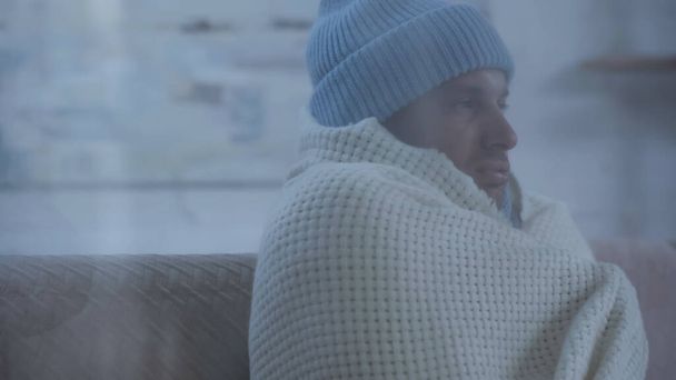 sick man in warm hat and blanket sitting on couch at home - Foto, Bild
