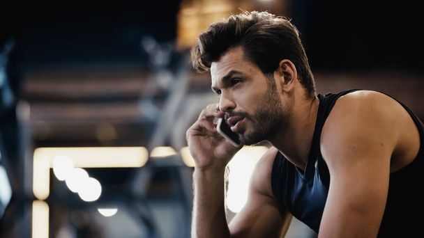 bearded young sportsman talking on smartphone in gym - Photo, Image