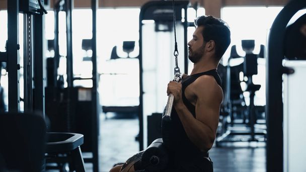 side view of sportsman training on fitness machine in gym  - Valokuva, kuva