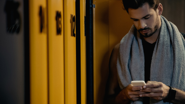 bearded sportsman messaging on smartphone in locker room - Valokuva, kuva