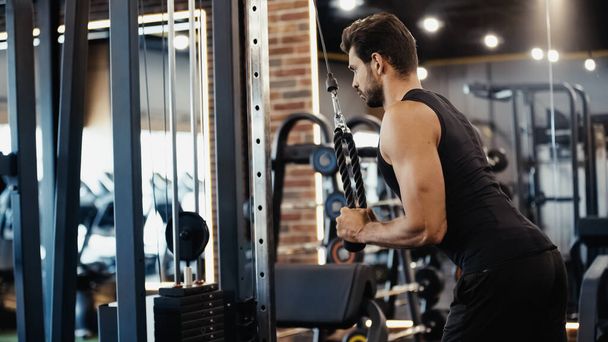 bearded sportsman exercising on fitness machine in sports center  - Photo, Image