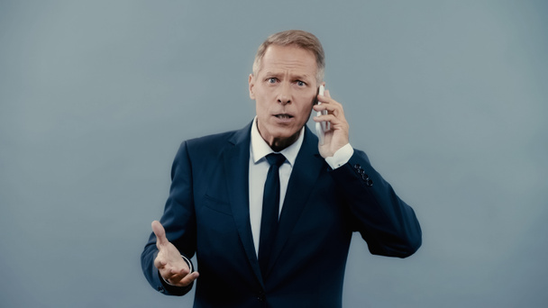 Mature businessman talking on smartphone and looking at camera isolated on grey  - Foto, Bild