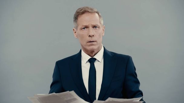 Middle aged businessman holding papers and looking at camera isolated on grey  - Фото, зображення
