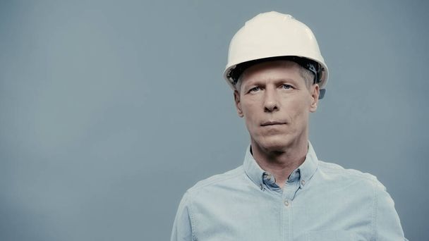 Mature engineer in hardhat looking at camera isolated on grey  - Фото, изображение