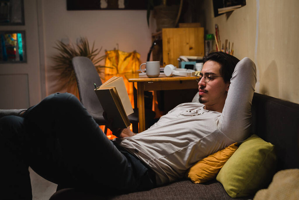 young man sitting in his room and reading book - Foto, Bild