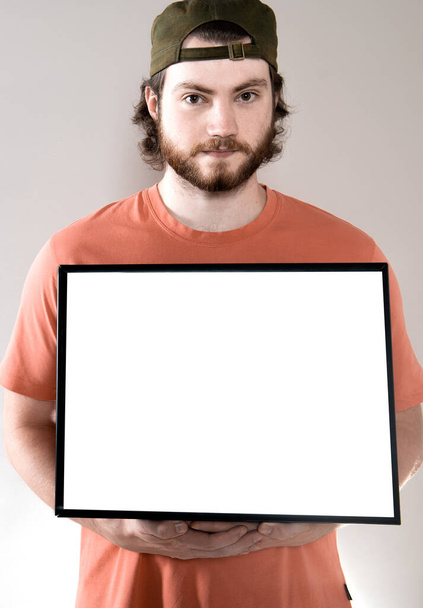 Mladý pohledný vousatý muž ukazující prázdný tabule, izolované na šedém pozadí - Fotografie, Obrázek