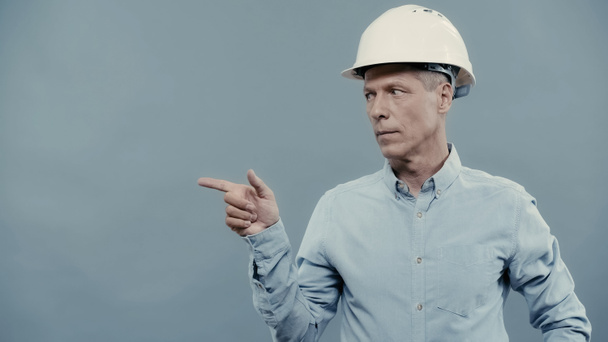 Middle aged businessman in hardhat pointing with finger isolated on grey  - Fotoğraf, Görsel