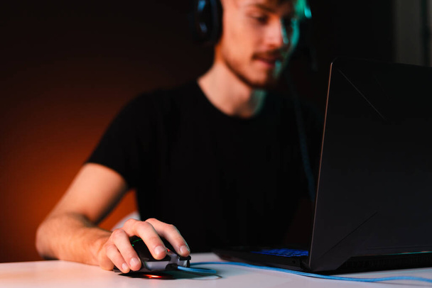 Gamer playing video games with headphones on neon light background - Photo, Image