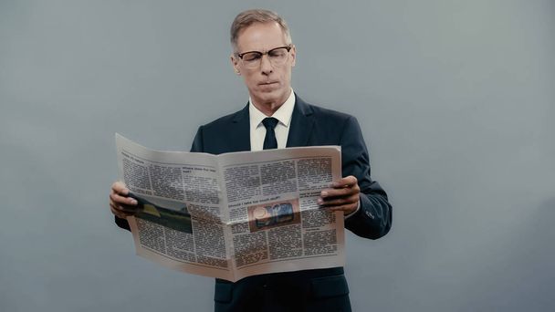 灰色で隔離された訴訟読書新聞で中年実業家  - 写真・画像