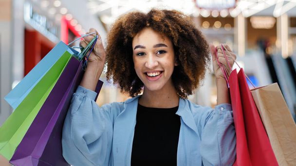 Close-up contented happy african american woman girl holding bright shopping bags purchases packages enjoy discounts looking at camera smiling broadly showing bought gifts for holidays sale concept - Photo, Image