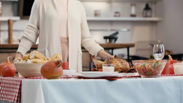 cropped view of blurred woman standing near festive dinner served for thanksgiving - Foto, Imagen