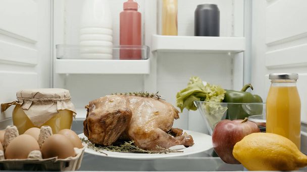 roasted turkey prepared for thanksgiving dinner near fresh vegetables, fruits and containers with food in fridge - Photo, Image