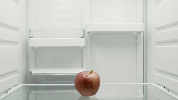 ripe red apple on shelf in empty fridge - Foto, Imagen
