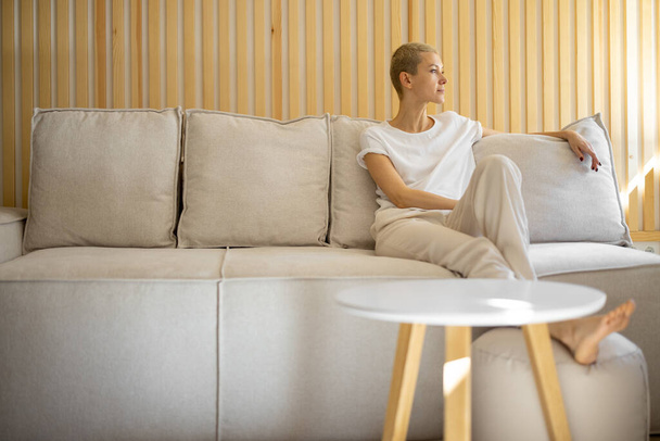 Woman sit and rest on sofa at home - Foto, Bild