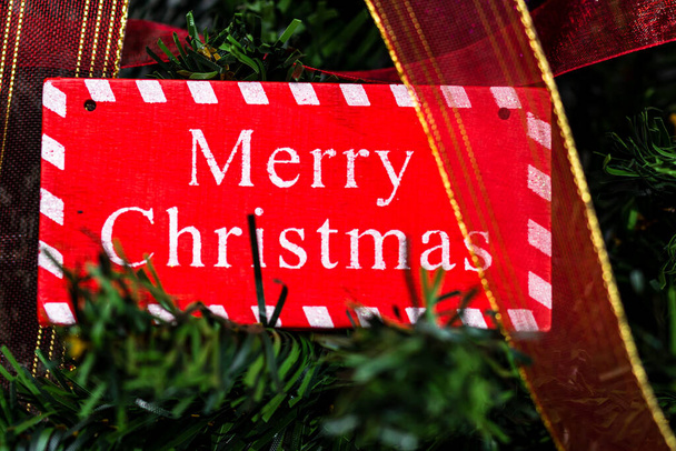 Merry Christmas sign hanging in the Christmas tree - Fotó, kép