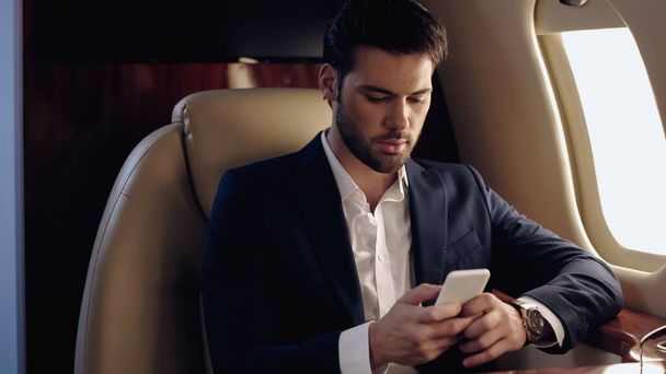 Businessman using smartphone in private plane  - Foto, immagini