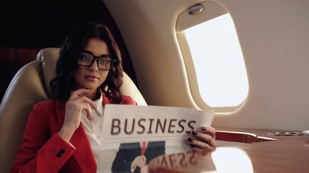 Young businesswoman reading blurred newspaper in private plane  - Zdjęcie, obraz