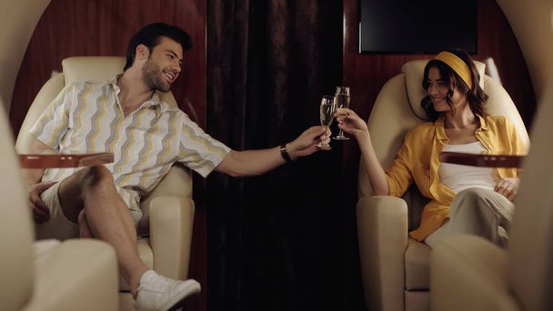 Sonriente pareja tintineando champán en jet privado  - Foto, Imagen