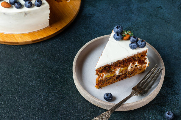 piece of carrot cake with walnuts and blueberry on dark background. Local food. Traditional american cake. Cake for thanksgiving day. Christmas cake - Фото, изображение