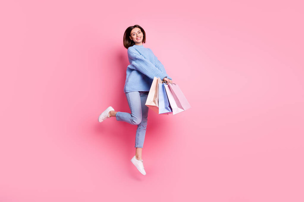 Full length body size view of attractive cheery cute girl jumping carrying bags isolated over pink pastel color background. - Photo, Image