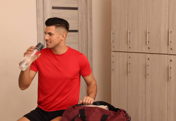Hombre guapo bebiendo agua en el vestuario
 - Foto, imagen