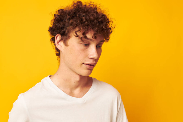 Cheerful guy with curly hair in a white T-shirt Youth style - Photo, image