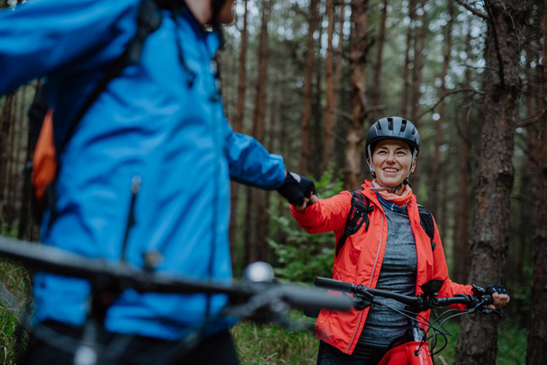 Senior couple bikers fist bumping outdoors in forest in autumn day. - Foto, immagini