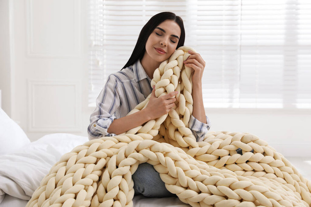 Young woman with chunky knit blanket on bed at home - Foto, Imagem