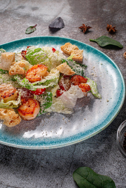 Healthy salad with fried shrimp, greens and croutons in a plate against a gray stone table. A healthy breakfast in a restaurant  - Fotoğraf, Görsel