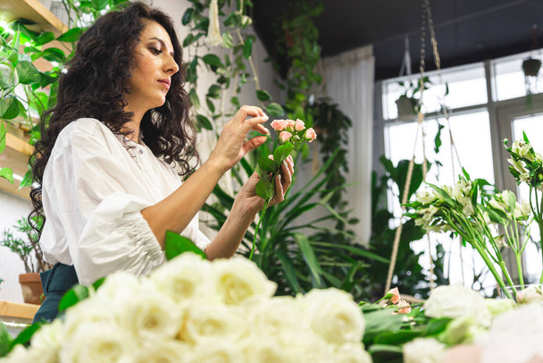 Attractive young woman florist is working in a flower shop. - Foto, imagen