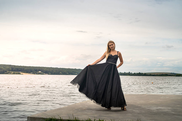 Красива молода жінка ввечері довга чорна сукня біля ставка, літній спосіб життя
 - Фото, зображення