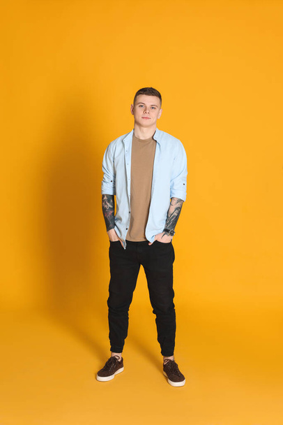 Young man with tattoos on yellow background - Photo, Image