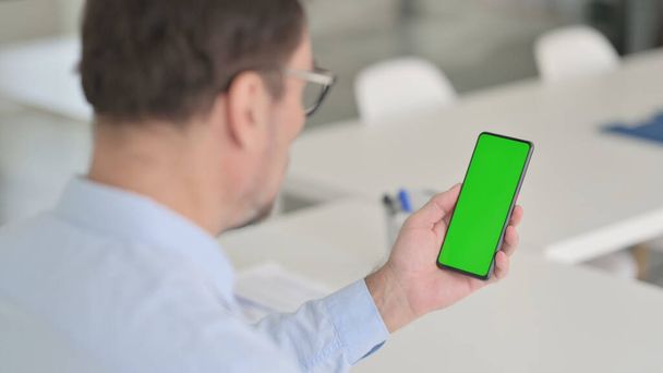 Hombre sosteniendo Smartphone con pantalla clave de croma verde - Foto, imagen