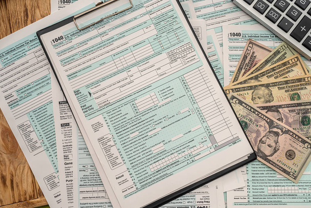 on a wooden table lie American tax forms, American dollar bills and a pen. Business concept - Photo, Image